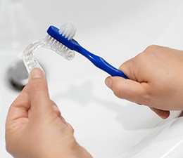 hands cleaning a nightguard over a sink