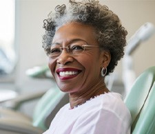 Woman in white shirt smiling while sitting in treatment chair