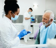Dentist showing patient model of denture during consultation