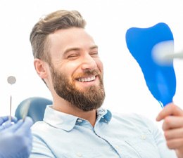 man smiling in dental mirror 