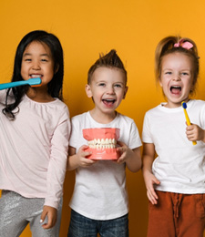 Three children smiling after receiving fluoride treatment in 