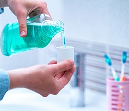 A man pouring mouthwash into a cup