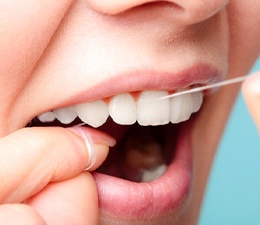 Close-up of woman flossing her upper teeth