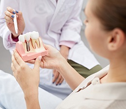 Dentist showing sample dental implant to patient