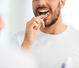 Nose-down reflection of man brushing his teeth in front of mirror