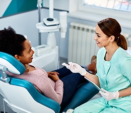 Dentist in mint green scrubs talking with patient in dental chair