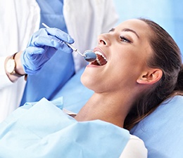 A woman lying back in the dentist’s chair allowing a professional to examine her smile after undergoing a root canal