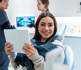 Patient smiling while holding mirror in treatment chair