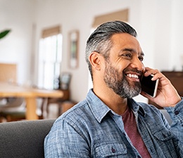 Man smiling while talking on phone at home
