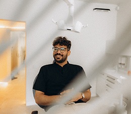 Patient with black glasses smiling in treatment chair