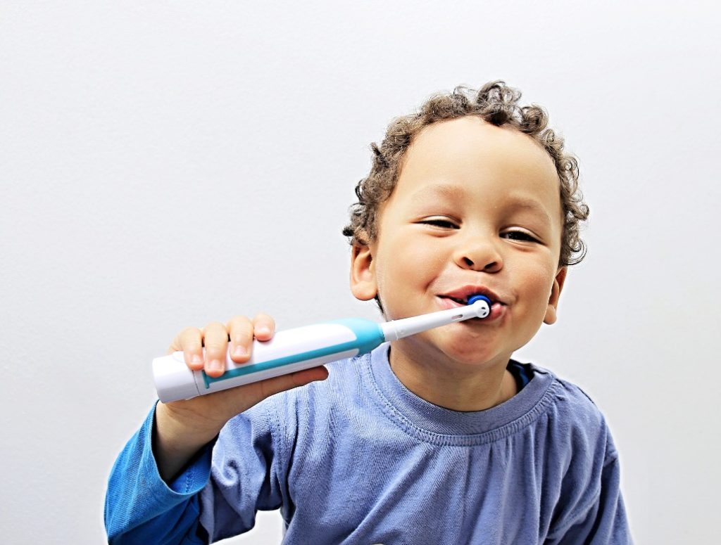 Little boy brushing his teeth at a family dentist visit 