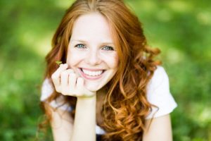 Young woman smiling after seeing family dentist in Waterbury